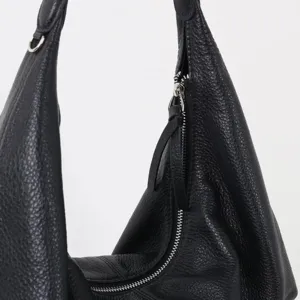 Gros plan détaillé d'un sac porté épaule en cuir souple avec fermeture éclair argentée.