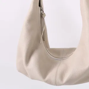 Gros plan détail d'un sac porté épaule souple en cuir beige avec fermeture éclair.