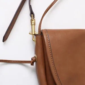 Vue de détail montrant la lanière du sac à épaule en cuir marron et le fermoir en métal.