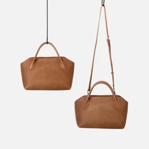 Détail du sac à main en cuir marron avec une texture fine et une sangle de transport.