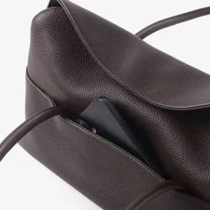 Gros plan sur les details de la poche avant en cuir souple marron de ce sac chic.