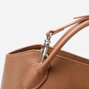 Vue détaillée des ferrures en métal et des coutures d'un sac à main en cuir véritable.