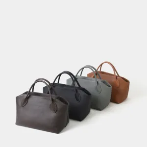 Vue détaillée du sac à main minimaliste en cuir véritable avec texture fine et options de couleur.
