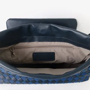 Vue intérieure détaillée d'un sac clutch tressé en cuir avec une poche zippée sécurisée.