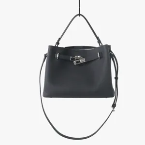 Détail du sac à main en cuir noir avec serrure argentée et poignée de transport robuste.