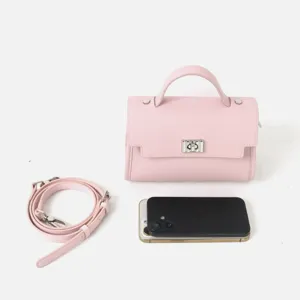 Sac bandoulière en cuir rose avec poignée, sangle réglable et fermoir métallique pour femme.