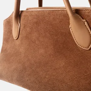 Gros plan détaillé du sac à main en daim marron montrant la poignée et la texture.