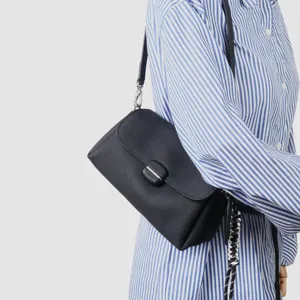 Detalle de bolso de cuero negro con textura de piel suave y cierre metálico elegante.