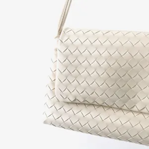 Vue détaillée du sac à main en cuir tissé blanc avec fermeture à rabat et texture élégante.