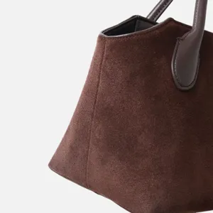 Vue détaillée d'un sac à main en daim marron montrant sa texture et sa poignée solide.