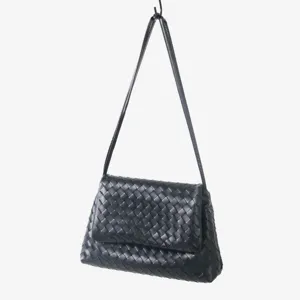 Détail du sac à rabat tissé en cuir noir, style élégant et décontracté sous les aisselles.