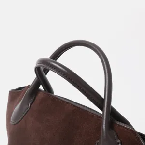 Gros plan sur la poignée de sac à main en cuir suédé marron, cabas minimaliste élégant.
