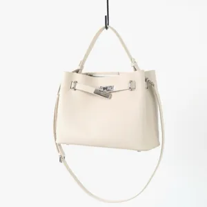 Détails du sac à main en cuir beige avec fermeture tournante en métal et bandoulière chic.