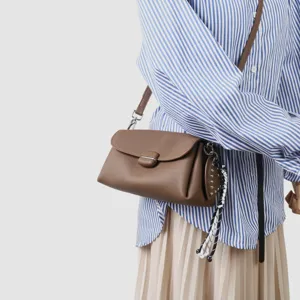 Vista detallada del bolso bandolera de cuero marrón con diseño de solapa elegante y correa.