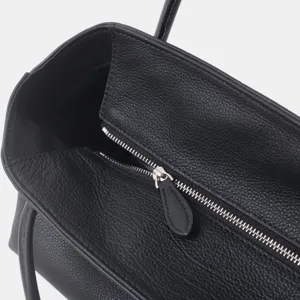 Gros plan détaillé de la fermeture éclair du sac cabas en cuir noir texturé.