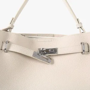 Vue détail du sac en cuir avec serrure métallique et texture de cuir de vachette.