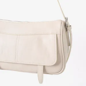 Détail de sac porté épaule en cuir tanné végétal, sac rétro minimaliste sous les bras.