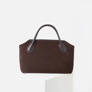 Vue détaillée d'un sac à main en daim marron foncé, texture élégante et style minimaliste.