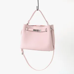 Détail de sac à main en cuir rose avec fermeture à tourniquet en métal et poignée.