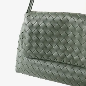 Vue rapprochée d'un sac à main en cuir tressé vert mettant en valeur la texture et le design.