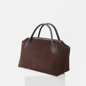 Détail sac à main en daim marron, poignées en cuir lisse, sac de navette vintage.