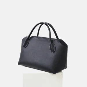 Vue de détail d'un sac à main noir en cuir véritable avec poignées, style rétro élégant.