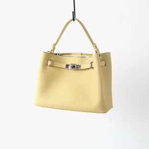 Vue détaillée du sac à main en cuir jaune avec fermeture tournante et poignée robuste.