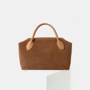Vue détaillée du sac à main en daim marron avec texture douce, poignées en cuir et belles finitions.