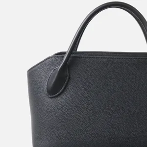 Vue détaillée de la poignée et de la structure supérieure d'un sac cabas en cuir noir.