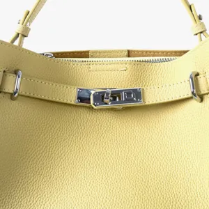Detail de sac a main en cuir veritable jaune, fermeture tourniquet, style chic.