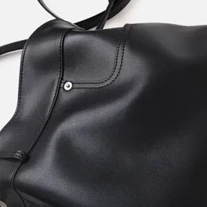 Sac bandoulière hobo en cuir souple noir, détail de texture premium et coutures fines.