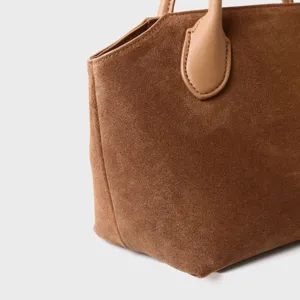 Vue détaillée du sac cabas en daim marron, mettant en valeur la texture et les coutures.
