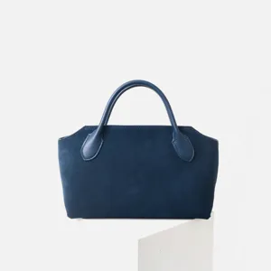 Gros plan détaillé du sac à main en daim bleu foncé montrant une texture et des poignées.