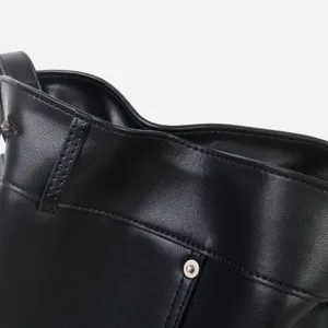 Gros plan des détails du sac en cuir noir, texture de couture et quincaillerie en métal.