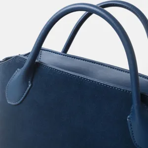 Gros plan des détails de la poignée du sac cabas en daim bleu et belles coutures.