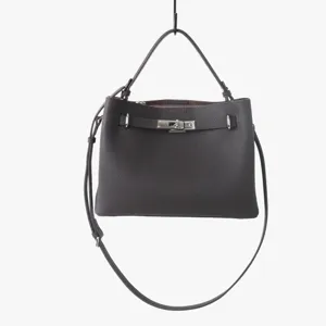 Détail rapproché du sac à bandoulière en cuir marron foncé avec fermoir tournant métallique.