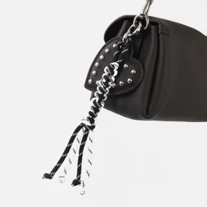 Vista detallada de un bolso de cuero marrón oscuro con colgante de corazón y cuerda trenzada.