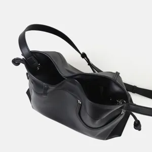 Détail de sac porté épaule hobo en cuir souple noir, élégant sac seau avec nœud élégant.