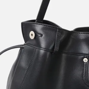 Détail de sac hobo en cuir noir, gros plan sur la texture souple avec fermeture aimantée.