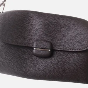Primer plano detalle del bolso de hombro de cuero genuino marron con cadena y cierre elegante.