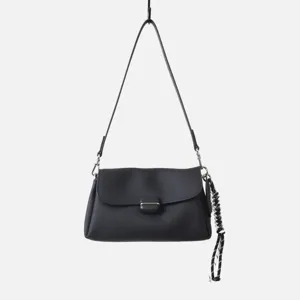 Detalles cercanos del bolso de hombro de cuero suave negro con cierre metálico y adorno trenzado.