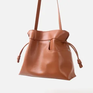 Sac bandoulière en cuir souple marron avec fermeture à cordon chic et détails de nœuds sur les côtés.