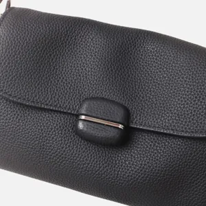Primer plano detalle de bolso de hombro de cuero de vaca suave negro con cierre metálico.