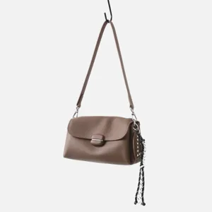 Detalle de bolso de hombro de cuero marrón con textura suave, cierre metálico y trenza.