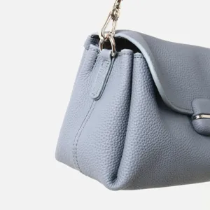 Detalle en primer plano de bolso de cuero gris con textura de grano suave y herrajes metálicos.