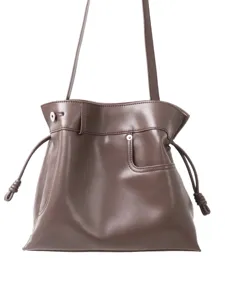 Élégant sac porté épaule marron en cuir souple pour femme avec liens coulissants noués.