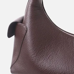 Primer plano detallado de un bolso de hombro de piel de vacuno marrón oscuro texturizada.