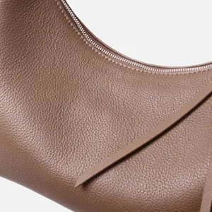 Primer plano de bolso de hombro de piel vacuno con textura fina y detalle de cremallera.