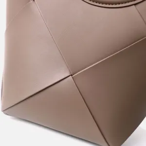 Close-up of premium wide woven leather handbag detail showing fine texture and modern design.