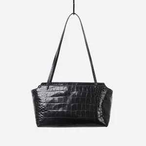 Detailed view of black crocodile embossed genuine leather shoulder bag hanging on white background.